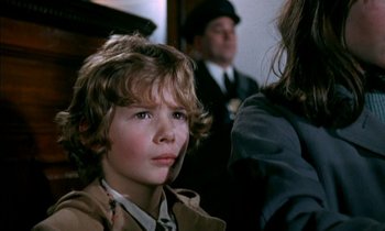 Movie still from “Our Mother's House” (1967), directed by Jack Clayton – A young boy sitting in front of a group of people; Close Up shot, Over the shoulder angle