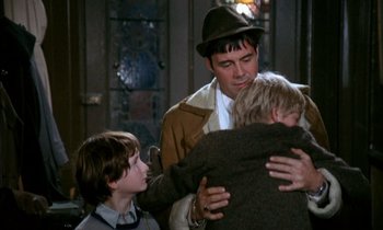 Movie still from “Our Mother's House” (1967), directed by Jack Clayton – A man is hugging two boys in front of a building; Medium shot, Over the shoulder angle
