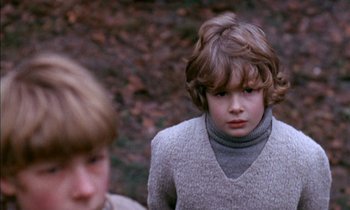 Movie still from “Our Mother's House” (1967), directed by Jack Clayton – A young boy in a grey sweater looks at the camera while a younger boy in a gray sweater looks at the camera; Close Up shot, Over the shoulder angle
