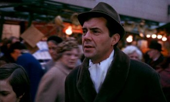 Movie still from “Our Mother's House” (1967), directed by Jack Clayton – A man wearing a hat and a brown coat walking down a street; Close Up shot, Over the shoulder angle