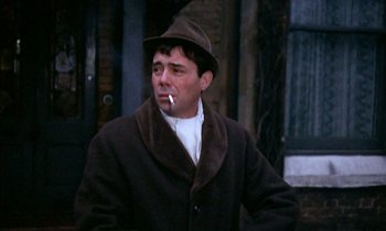 Movie still from “Our Mother's House” (1967), directed by Jack Clayton – A man wearing a brown coat and a brown hat smoking a cigarette; Close Up shot, Low angle