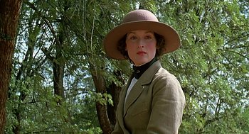 Movie still from “Out of Africa” (1985), directed by Sydney Pollack – A woman wearing a hat standing in front of a tree; Close Up shot, Low angle