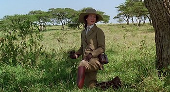 Movie still from “Out of Africa” (1985), directed by Sydney Pollack – A woman in a hat is standing in the grass; Medium shot, Low angle