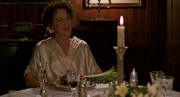 Movie still from “Out of Africa” (1985), directed by Sydney Pollack – A woman sitting at a table with a plate of food; Medium shot, Over the shoulder angle