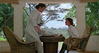 Movie still from “Out of Africa” (1985), directed by Sydney Pollack – Two people sitting at a table with a cup of tea; Medium shot, Over the shoulder angle