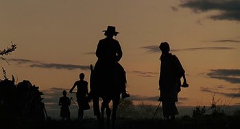 Movie still from “Out of Africa” (1985), directed by Sydney Pollack – A group of people riding horses on a field; Wide shot, Low angle