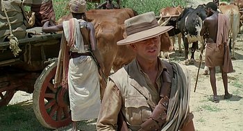 Movie still from “Out of Africa” (1985), directed by Sydney Pollack – A man in a hat standing in front of a herd of cattle; Medium shot, Over the shoulder angle