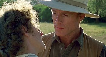 Movie still from “Out of Africa” (1985), directed by Sydney Pollack – An older man and a young woman in a field with trees in the background; Close Up shot, Over the shoulder angle