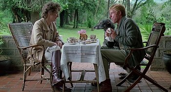 Movie still from “Out of Africa” (1985), directed by Sydney Pollack – A man and a woman sitting at a table; Medium shot, Over the shoulder angle