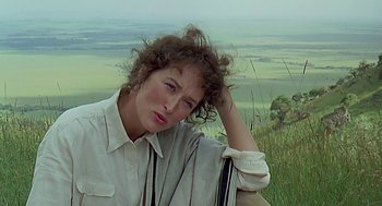 Movie still from “Out of Africa” (1985), directed by Sydney Pollack – A woman sitting on top of a grass covered hill; Close Up shot, Over the shoulder angle