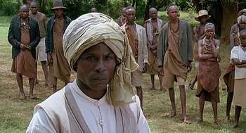 Movie still from “Out of Africa” (1985), directed by Sydney Pollack – A group of men standing in the grass; Medium shot, Over the shoulder angle