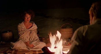 Movie still from “Out of Africa” (1985), directed by Sydney Pollack – A woman sitting in front of a fire at night; Medium shot, High angle