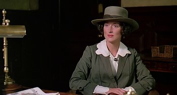 Movie still from “Out of Africa” (1985), directed by Sydney Pollack – A woman wearing a hat sitting at a table; Close Up shot, Over the shoulder angle