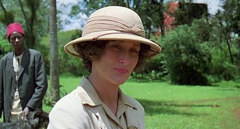 Movie still from “Out of Africa” (1985), directed by Sydney Pollack – A woman wearing a tan hat in a field; Close Up shot, Over the shoulder angle