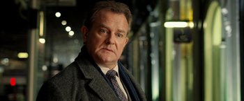 Movie still from “Paddington” (2014), directed by Paul King – A person wearing a suit and tie; Close Up shot, Over the shoulder angle