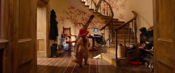 Movie still from “Paddington” (2014), directed by Paul King – A teddy bear is standing in the middle of a room; Wide shot, High angle