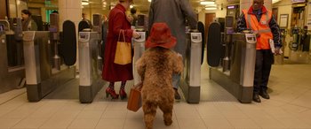 Movie still from “Paddington” (2014), directed by Paul King – A dog with a red hat and a brown suitcase; Wide shot, Low angle