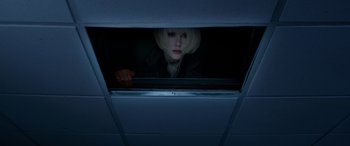 A woman looking out of a window in a dark room
