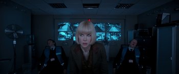 Movie still from “Paddington” (2014), directed by Paul King – A woman in front of a video wall in a room; Medium shot, Over the shoulder angle