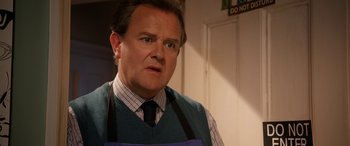 Movie still from “Paddington” (2014), directed by Paul King – A man wearing a blue apron in a room; Close Up shot, Over the shoulder angle