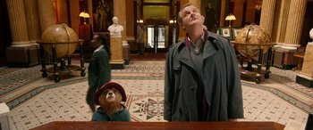 Movie still from “Paddington” (2014), directed by Paul King – A man and a woman standing next to each other in a room; Medium shot, Low angle