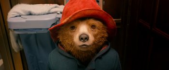 Movie still from “Paddington” (2014), directed by Paul King – A brown bear wearing a red hat and a blue jacket; Close Up shot, Low angle
