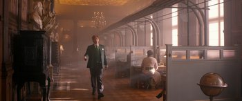 Movie still from “Paddington” (2014), directed by Paul King – A man in a suit walking through a room; Wide shot, Low angle