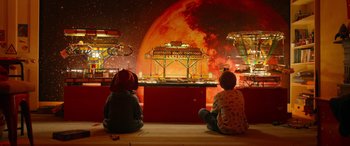 Movie still from “Paddington” (2014), directed by Paul King – Two children sitting on the ground looking at an exhibit; Wide shot, High angle