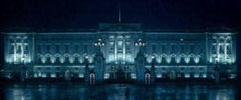 Movie still from “Paddington” (2014), directed by Paul King – A large building lit up at night in the rain; Extreme Wide shot, Low angle