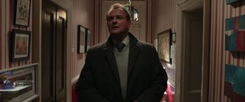 Movie still from “Paddington” (2014), directed by Paul King – A man in a suit and tie standing in a hallway; Medium shot, Low angle