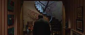 Movie still from “Paddington” (2014), directed by Paul King – A man sitting in front of a spiral stair case; Wide shot, High angle