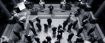 Movie still from “Paddington” (2014), directed by Paul King – A group of people standing in a circle in front of a man; Extreme Wide shot, Overhead angle