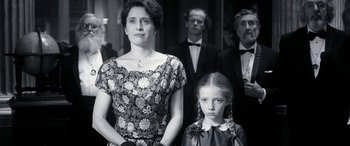 Movie still from “Paddington” (2014), directed by Paul King – A woman and a little girl standing next to each other in front of other people; Medium shot, Over the shoulder angle