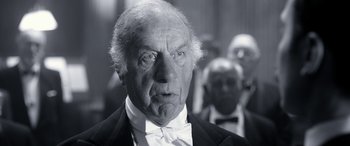 Movie still from “Paddington” (2014), directed by Paul King – An old man wearing a tuxedo and a bow tie; Close Up shot, Low angle