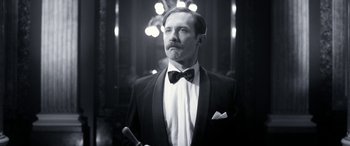 Movie still from “Paddington” (2014), directed by Paul King – A black and white photo of a man in a tuxedo holding a cane; Close Up shot, Low angle