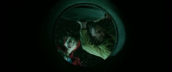 Movie still from “Paddington” (2014), directed by Paul King – A man and a boy looking through a hole in the wall; Medium shot, Overhead angle