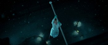 Movie still from “Paddington” (2014), directed by Paul King – A young child hanging from a pole in a dark room; Wide shot, Overhead angle