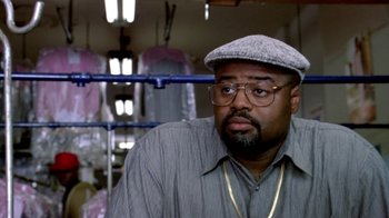 Movie still from “Paid in Full” (2002), directed by Charles Stone III – A man wearing glasses and a hat in a room; Close Up shot, Low angle