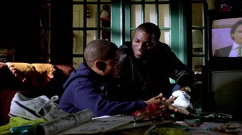 Movie still from “Paid in Full” (2002), directed by Charles Stone III – A man and a boy sitting at a table; Medium shot, Low angle
