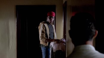 Movie still from “Paid in Full” (2002), directed by Charles Stone III – A man in a red hat standing in front of a mirror; Medium shot, Over the shoulder angle