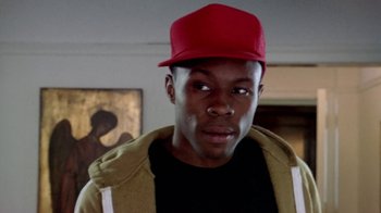 Movie still from “Paid in Full” (2002), directed by Charles Stone III – A man wearing a red hat in a living room; Close Up shot, Low angle