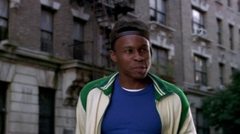 Movie still from “Paid in Full” (2002), directed by Charles Stone III – A man in a baseball cap is standing in front of an apartment building; Close Up shot, Low angle