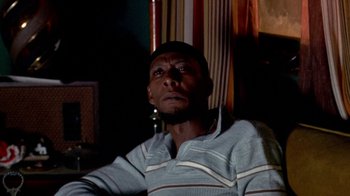 Movie still from “Paid in Full” (2002), directed by Charles Stone III – A man sitting in front of a curtain looking up; Close Up shot, Low angle