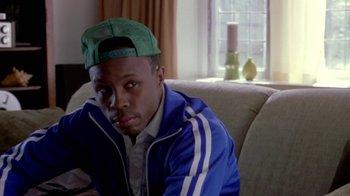 Movie still from “Paid in Full” (2002), directed by Charles Stone III – A man sitting on top of a couch in a living room; Close Up shot, High angle