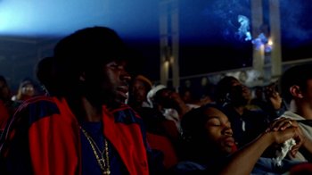 Movie still from “Paid in Full” (2002), directed by Charles Stone III – A group of people sitting in a stadium watching a game; Medium shot, Low angle