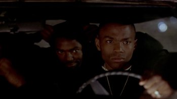 Movie still from “Paid in Full” (2002), directed by Charles Stone III – A couple of men standing next to each other in front of a steering wheel; Close Up shot, Over the shoulder angle