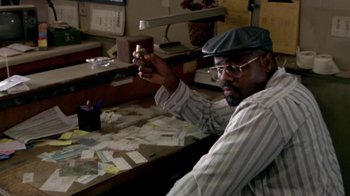 Movie still from “Paid in Full” (2002), directed by Charles Stone III – A man sitting at a table holding a candle; Medium shot, Low angle