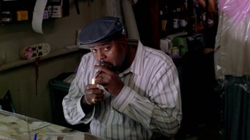 Movie still from “Paid in Full” (2002), directed by Charles Stone III – A man sitting down and drinking a cup of coffee; Medium shot, Low angle