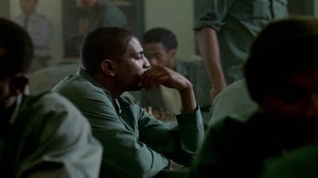 Movie still from “Paid in Full” (2002), directed by Charles Stone III – A man sitting in front of a group of people; Close Up shot, Over the shoulder angle