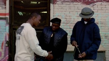 Movie still from “Paid in Full” (2002), directed by Charles Stone III – A group of men standing next to each other on a sidewalk; Medium shot, Low angle